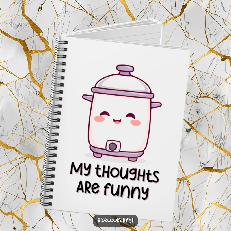 Funny smiling rice cooker character with lid tilted in amusement, featured on a notebook for jotting down ideas.
